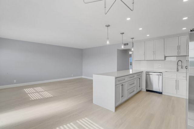 kitchen featuring kitchen peninsula, hanging light fixtures, sink, stainless steel dishwasher, and light wood-type flooring