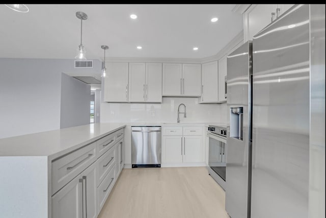 kitchen with stainless steel appliances, white cabinetry, kitchen peninsula, hanging light fixtures, and light hardwood / wood-style flooring