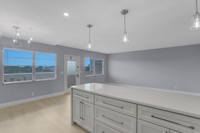 kitchen with white cabinetry, light wood-type flooring, decorative light fixtures, and a notable chandelier