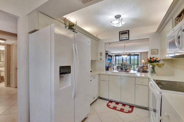 kitchen with light tile patterned floors, white appliances, white cabinets, and a textured ceiling