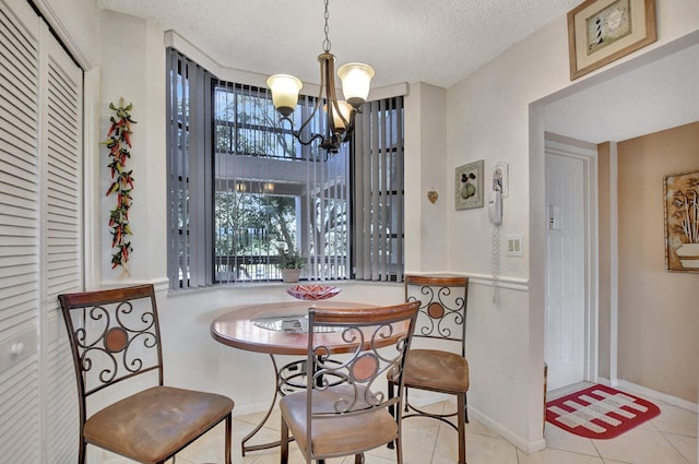 tiled dining space featuring a chandelier and a textured ceiling