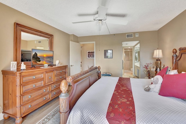 bedroom with ceiling fan, light hardwood / wood-style floors, a textured ceiling, and ensuite bath