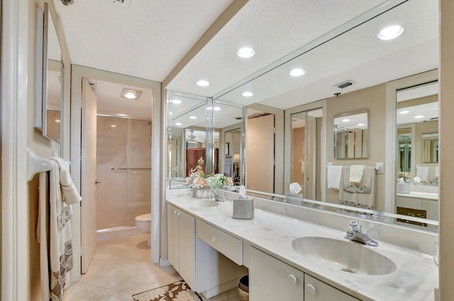 bathroom featuring tile patterned flooring, vanity, a shower with shower door, and toilet