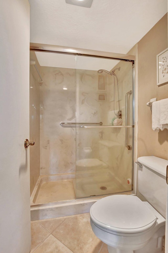 bathroom featuring tile patterned flooring, an enclosed shower, and toilet