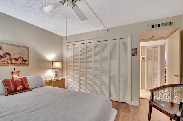 bedroom with ceiling fan, light hardwood / wood-style flooring, a closet, and a textured ceiling