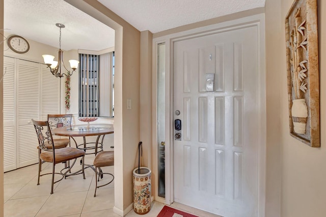 tiled entrance foyer featuring a textured ceiling and an inviting chandelier