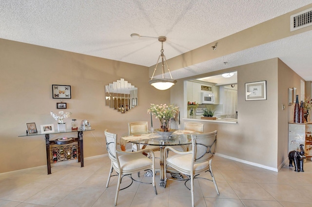 tiled dining space with a textured ceiling