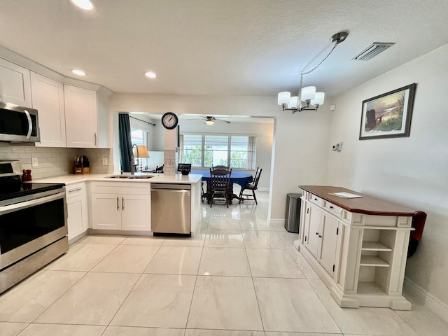 kitchen with sink, stainless steel appliances, decorative light fixtures, and light tile patterned floors