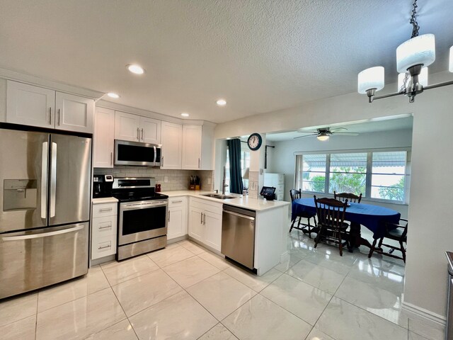 kitchen with appliances with stainless steel finishes, white cabinets, decorative backsplash, and kitchen peninsula