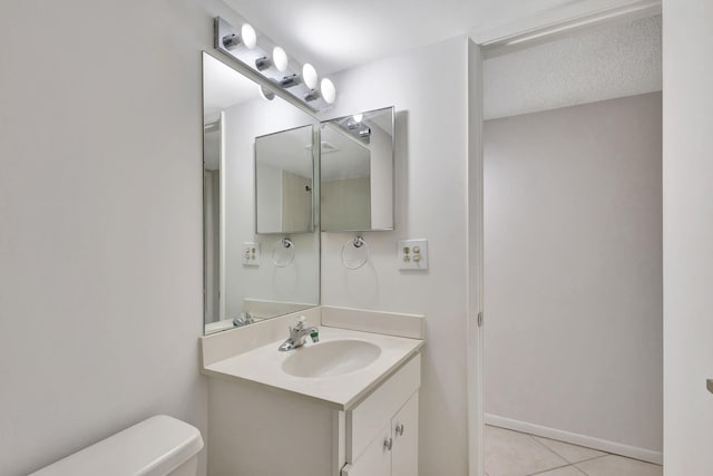 bathroom featuring tile patterned flooring, toilet, vanity, and a textured ceiling