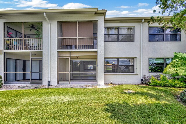 rear view of property featuring a balcony and a lawn