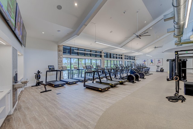 exercise room with light hardwood / wood-style floors, a high ceiling, and ceiling fan