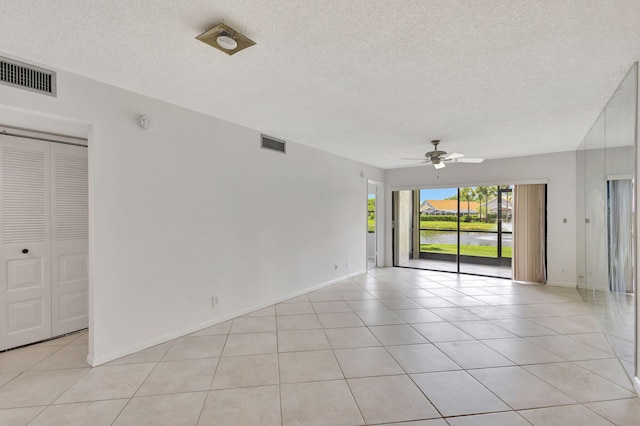 empty room with light tile patterned flooring, a textured ceiling, and ceiling fan