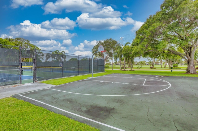 view of basketball court with tennis court and a yard