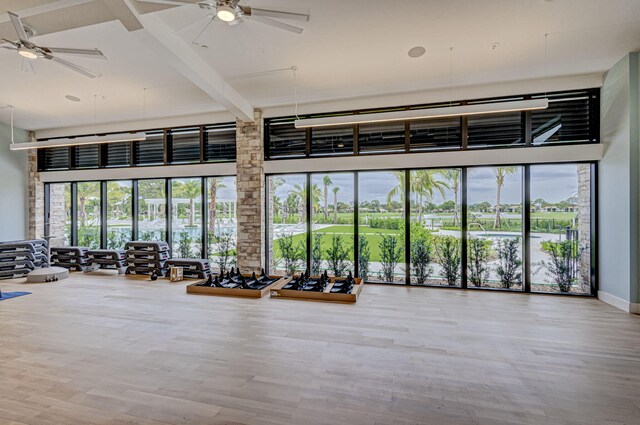 exercise room featuring ceiling fan, hardwood / wood-style floors, and a high ceiling