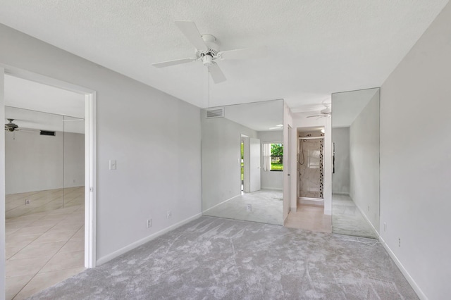 unfurnished bedroom featuring light carpet, ceiling fan, and a textured ceiling