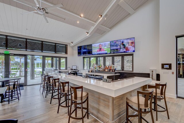 bar featuring ceiling fan, french doors, light hardwood / wood-style flooring, and high vaulted ceiling