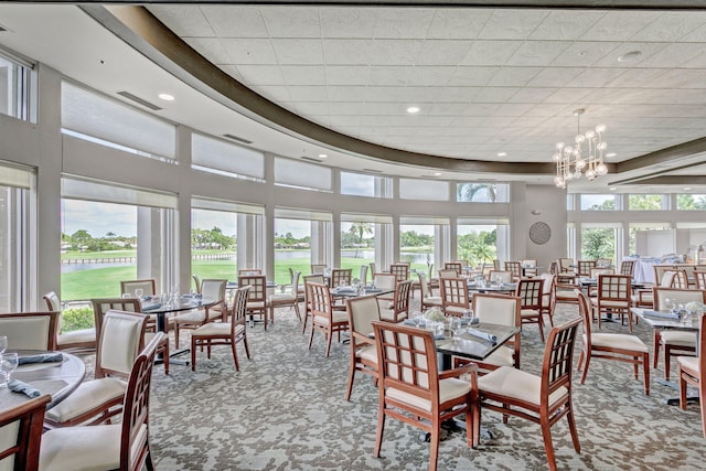 carpeted dining space with a chandelier and a high ceiling