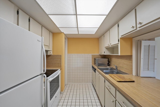 kitchen with white cabinetry, tile walls, white appliances, sink, and light tile patterned floors