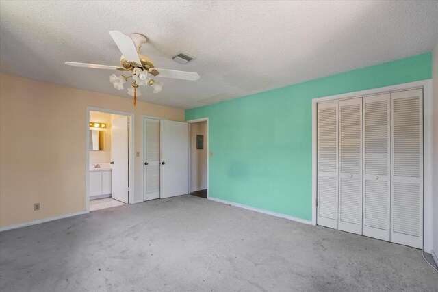 unfurnished bedroom with light carpet, ceiling fan, connected bathroom, and a textured ceiling