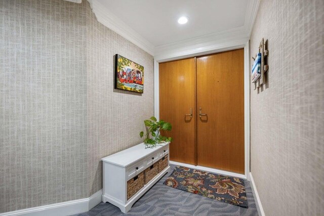 doorway with crown molding and carpet