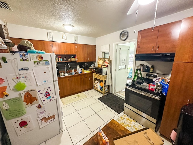 kitchen featuring stainless steel appliances, light tile patterned flooring, sink, and a textured ceiling