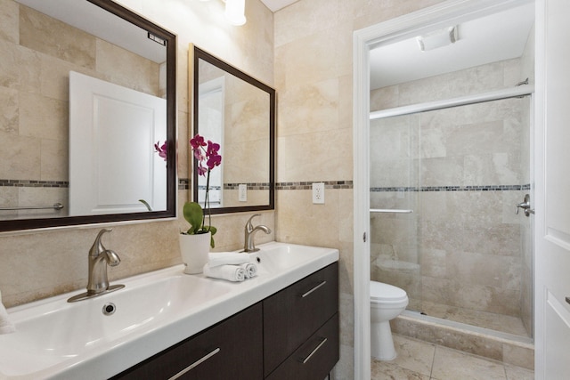 bathroom with tile walls, toilet, a shower with shower door, vanity, and tile patterned floors