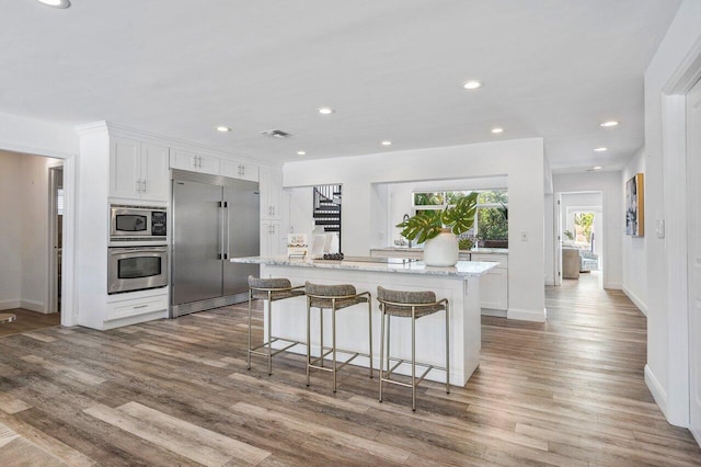 5533 Rico Dr, Boca Raton, FL 33487 - kitchen with built in appliances, wood finished floors, white cabinetry, a kitchen island, and recessed lighting