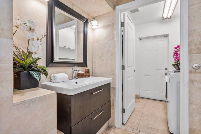 5533 Rico Dr, Boca Raton, FL 33487 - bathroom with vanity, tile walls, and marble look tiles