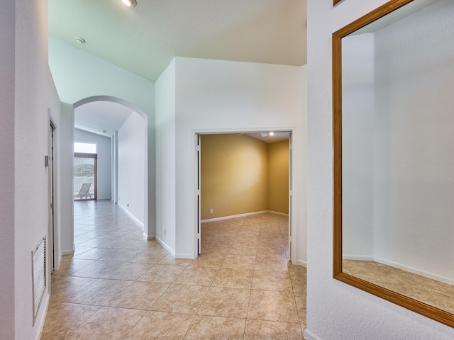 hallway featuring vaulted ceiling and light tile patterned flooring