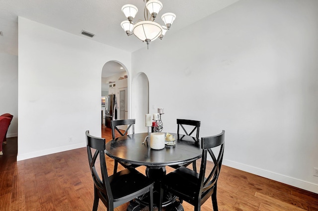 5890 NE 56th Pkwy, Okeechobee, FL 34972 - dining area featuring an inviting chandelier, arched walkways, visible vents, wood finished floors, and baseboards