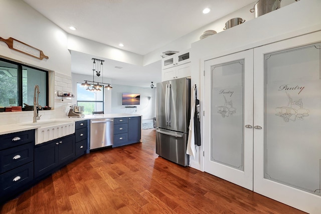 5890 NE 56th Pkwy, Okeechobee, FL 34972 - kitchen with a sink, a peninsula, dark wood-style floors, appliances with stainless steel finishes, and blue cabinets