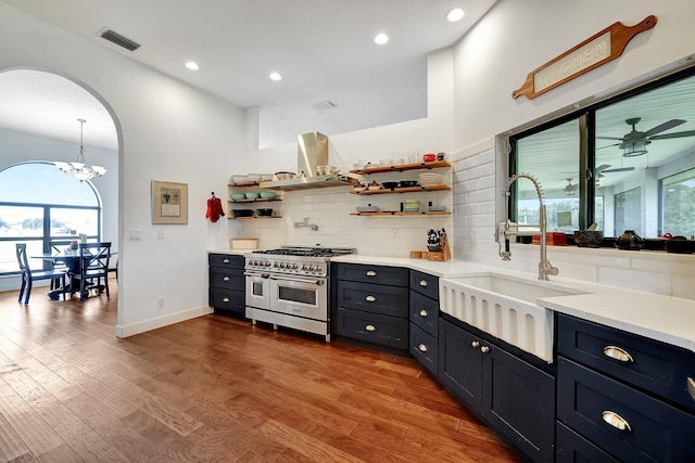 5890 NE 56th Pkwy, Okeechobee, FL 34972 - kitchen with open shelves, visible vents, wall chimney exhaust hood, double oven range, and a sink