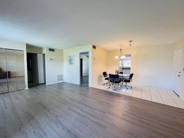 interior space featuring an inviting chandelier, a textured ceiling, and light hardwood / wood-style floors