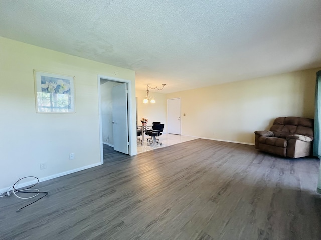 unfurnished living room featuring hardwood / wood-style flooring, an inviting chandelier, and a textured ceiling