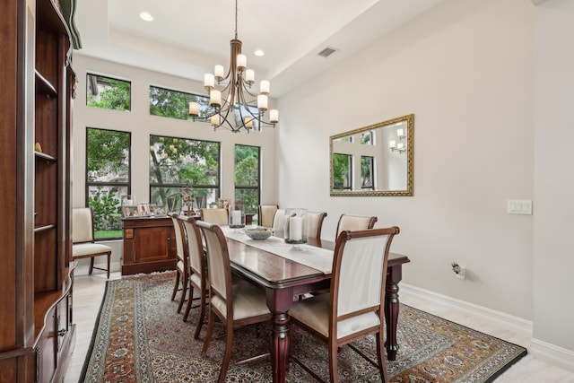 dining space featuring light hardwood / wood-style floors, a tray ceiling, and a notable chandelier