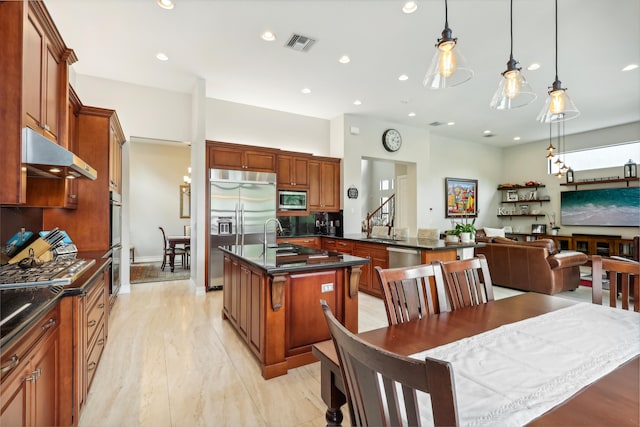 kitchen featuring built in appliances, hanging light fixtures, a center island, light hardwood / wood-style floors, and kitchen peninsula