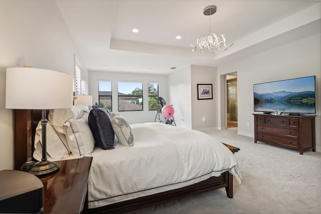 carpeted bedroom with an inviting chandelier, ensuite bath, and a tray ceiling