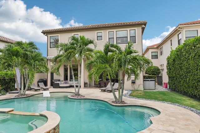 rear view of property featuring a swimming pool with hot tub, a patio, and an outdoor hangout area