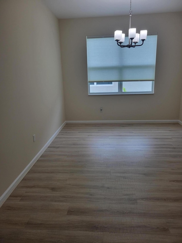 empty room featuring a notable chandelier and hardwood / wood-style floors