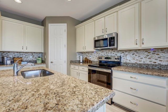 kitchen featuring sink, decorative backsplash, appliances with stainless steel finishes, and light stone countertops