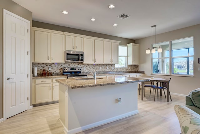 kitchen with hanging light fixtures, a wealth of natural light, decorative backsplash, and stainless steel appliances