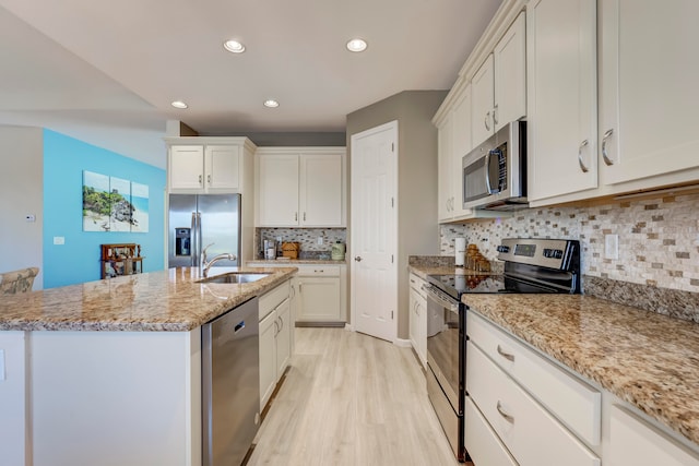 kitchen featuring tasteful backsplash, light hardwood / wood-style floors, appliances with stainless steel finishes, sink, and a center island with sink