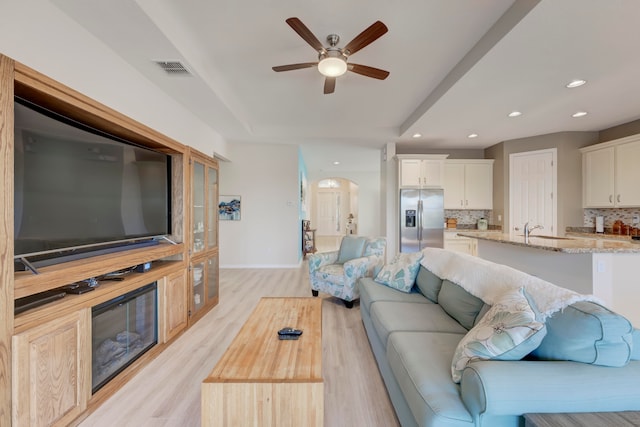 living room with light hardwood / wood-style floors, sink, and ceiling fan