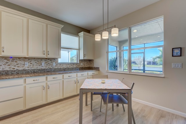 kitchen with hanging light fixtures, white cabinets, tasteful backsplash, and light wood-type flooring