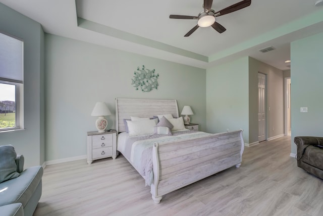 bedroom featuring a tray ceiling, light hardwood / wood-style flooring, and ceiling fan