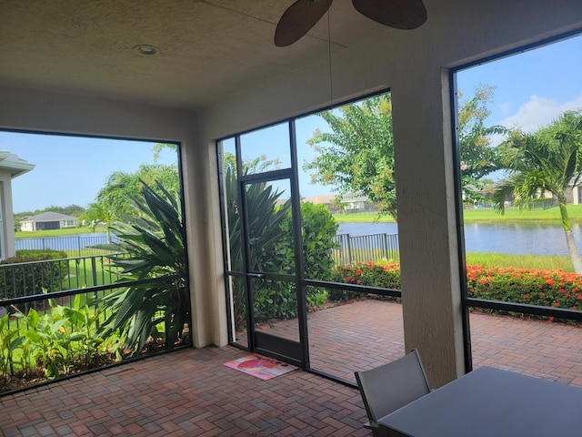 sunroom / solarium with a water view and ceiling fan