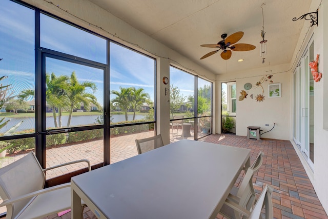 sunroom featuring a water view and ceiling fan