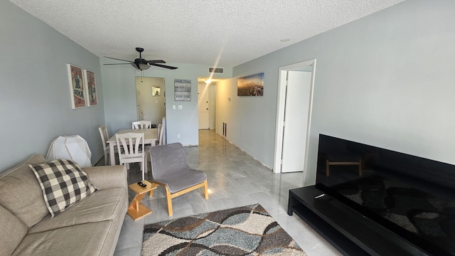 living area featuring marble finish floor, visible vents, ceiling fan, and a textured ceiling