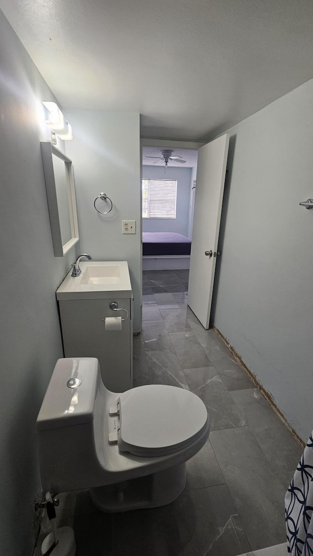 bathroom with toilet, vanity, and ceiling fan